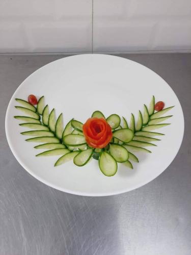 a white plate with a flower on top of green leaves at The Ontime Hotel, Bangalore in Bengaluru