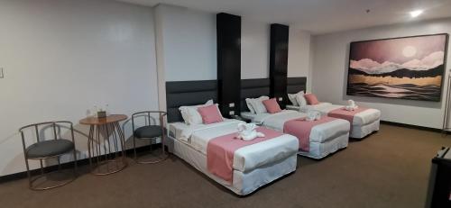 a room with three beds and a table and chairs at Palette in Angeles Pampanga near Clark International Airport Formerly Boss Hotel in Angeles