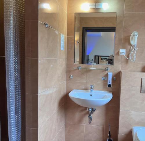 a bathroom with a sink and a mirror and a shower at Aura - Hotel & Restaurant & Sauna in Zielona Góra