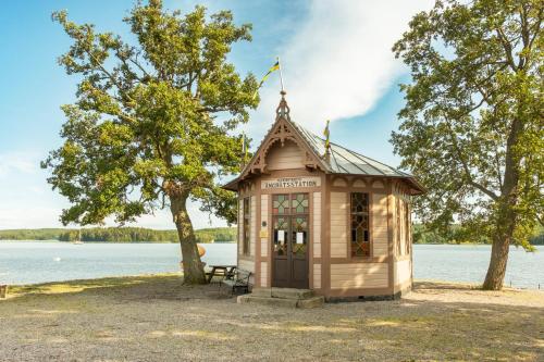 a small wooden building next to a body of water at Röda Magasinet in Mariefred