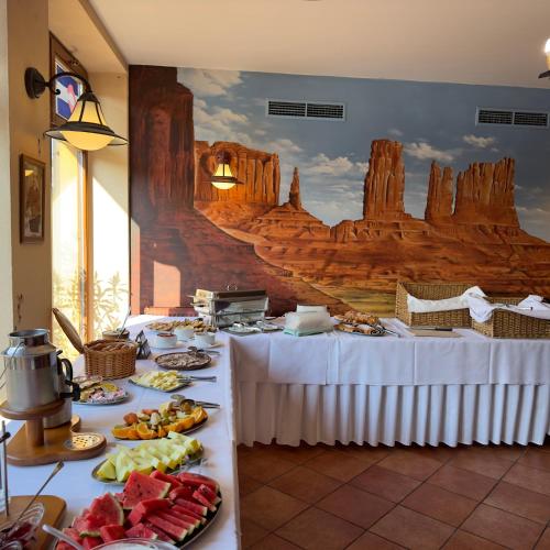 a buffet line with plates of food in front of a mural at Country Saloon Belá in Belá