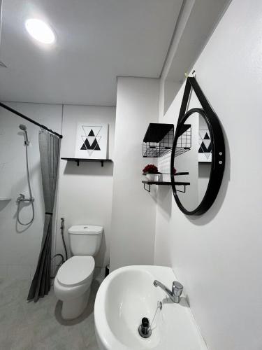 a white bathroom with a toilet and a sink at Condo Near Mactan Airport in Pusok