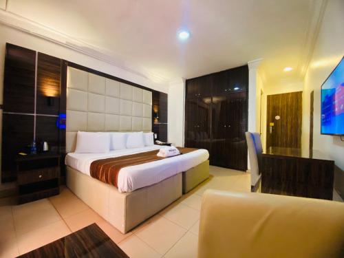 a hotel room with a bed and a chair and a television at Presken Hotels @ Victoria Island in Apese