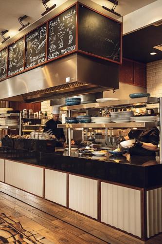 a kitchen with chefs preparing food in a restaurant at Airport Hotel Okęcie in Warsaw