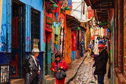 a group of people walking down a street in an alley at AQUI ME QUEDO here I Stay in Bogotá