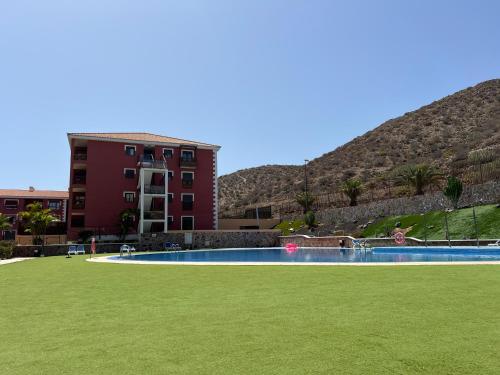a swimming pool in front of a building at Luminoso y Elegante, piscinas y pistas de pádel in Palm-mar
