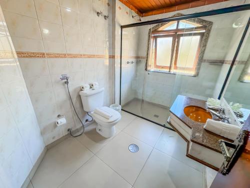 a bathroom with a toilet and a shower and a sink at Hotel Nacional Inn Campos do Jordão in Campos do Jordão