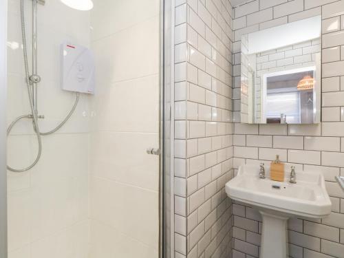 Un baño blanco con lavabo y ducha. en The Beach Condo, en Weymouth