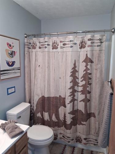 ein Badezimmer mit einem Duschvorhang mit einem Bären und Bäumen in der Unterkunft Bear Valley - Riverfront, Starlink WiFi & Hot Tub in Luray