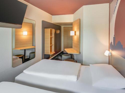 a room with two beds and a mirror at B&B HOTEL Kassel-Lohfelden in Kassel