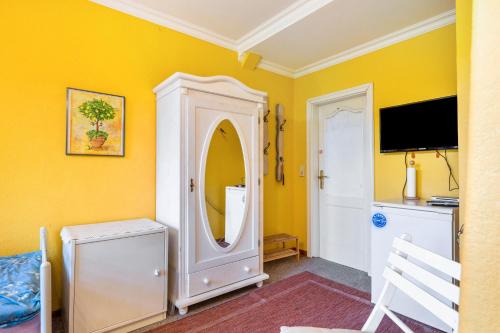 a yellow room with a mirror and a tv at Gästehaus Ziegler in Neuenkirchen