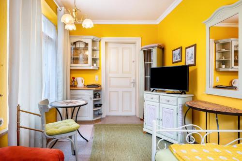 a living room with yellow walls and a tv at Gästehaus Ziegler in Neuenkirchen