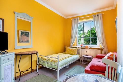 a yellow living room with a couch and a table at Gästehaus Ziegler in Neuenkirchen