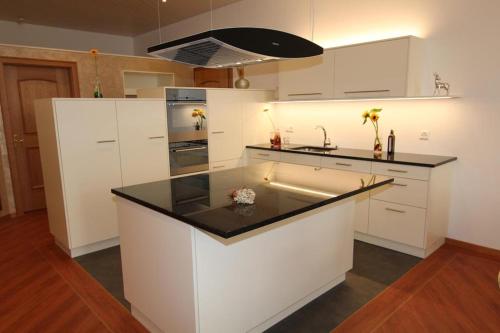 a kitchen with white cabinets and a black counter top at Seilers Vintage Hotel & Spa in Kandersteg