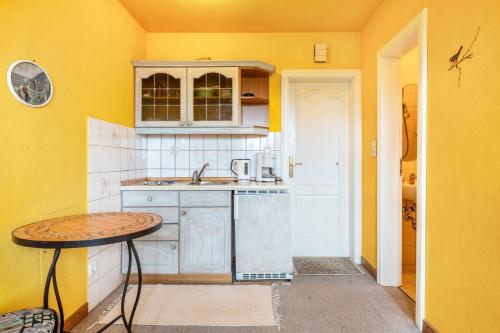 a kitchen with yellow walls and a sink and a table at Gästehaus Ziegler in Neuenkirchen