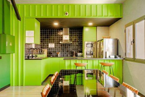 a green kitchen with a table and some chairs at Wonder Hostel in Toledo