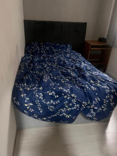 a bed with a blue comforter with white flowers on it at Budget Rooms & Beds in London in London