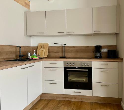 a kitchen with white cabinets and an oven at Ferienwohnung Pferdehof Birkholz in Bernau bei Berlin