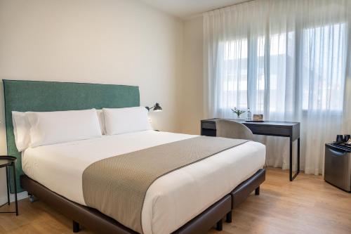 a bedroom with a large bed with a desk and a window at Tres Torres Atiram Hotel in Barcelona