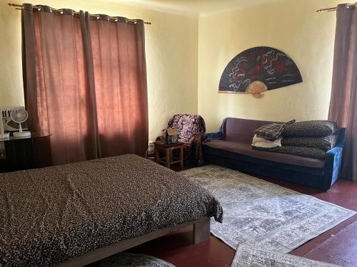 a bedroom with a bed and a couch and a chair at Dzērves apartamenti in Nastrova