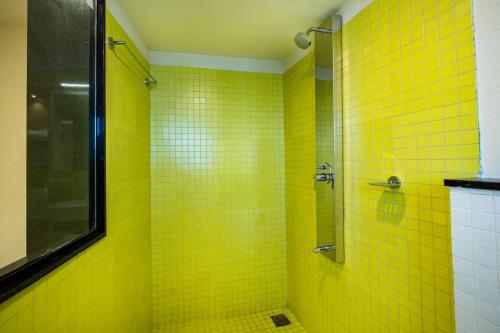 a yellow tiled bathroom with a shower with yellow tiles at Ascot Hotel Calicut in Calicut