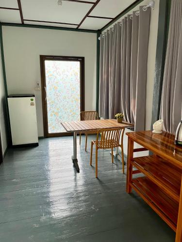 a dining room with a table and chairs and a window at The Summer Guesthouse in Ban Khlong Son