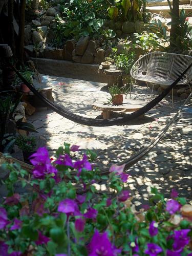 a bench sitting in a garden with purple flowers at Una Posada Mas in Mazunte
