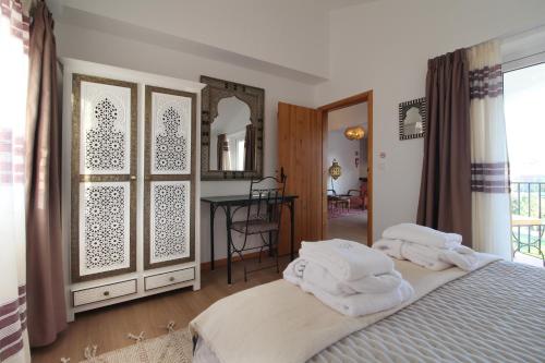 a bedroom with towels on a bed and a table at Quinta do Canal in Vila Nova de Milfontes
