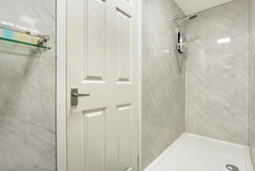 y baño con ducha y puerta blanca. en Finest Retreats - Kelsick Villa Guest House - Gummers How, en Ambleside