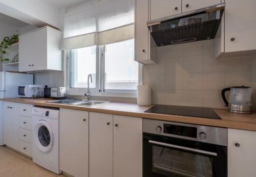 a white kitchen with a sink and a dishwasher at The Seven - One Bedroom Apartment in Paralimni
