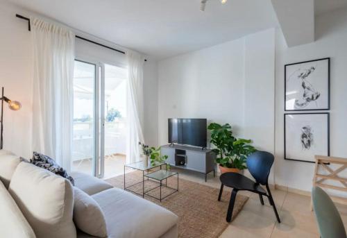 a living room with a white couch and a tv at The Seven - One Bedroom Apartment in Paralimni