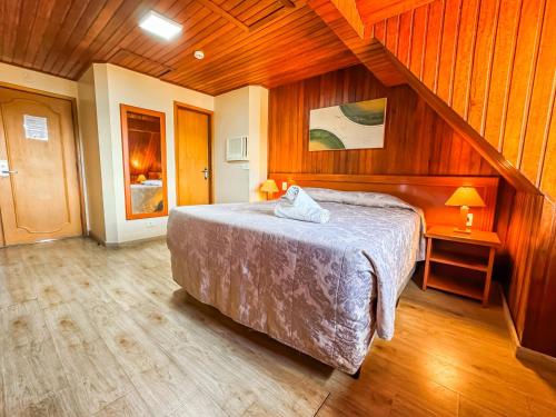 a bedroom with a bed and wooden walls and wooden floors at Hotel Nacional Inn Campos do Jordão in Campos do Jordão