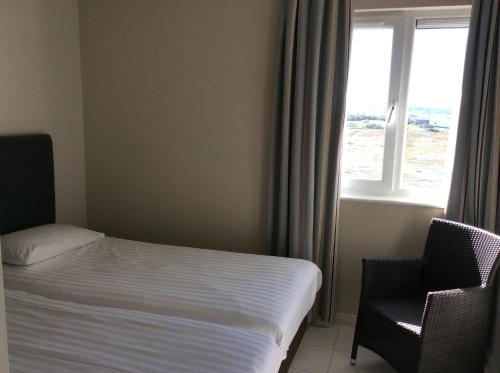 a bedroom with a bed and a window and a chair at Discovery Bay in St Ouen's