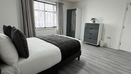 Un dormitorio con una cama y una cómoda. en 4 Bedroom House - Romford, en Dagenham