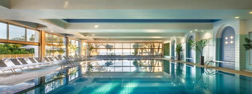 a swimming pool in a building with chairs at Remisens BEL MORETTO - Hotel Metropol Annexe in Portorož