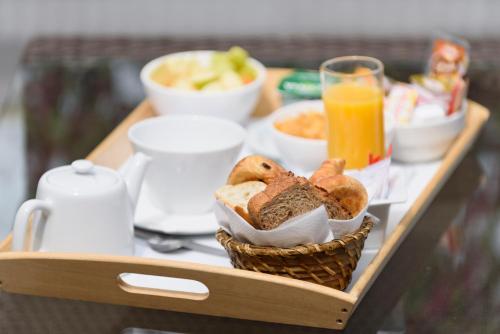 uma bandeja com uma cesta de pão e um copo de sumo de laranja em Best Western Astoria em Juan-les-Pins