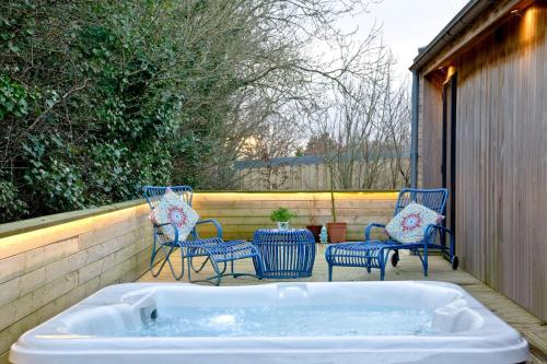a hot tub on a patio with chairs and a table at The Levels, Strawberryfield Park, Cheddar in Cheddar