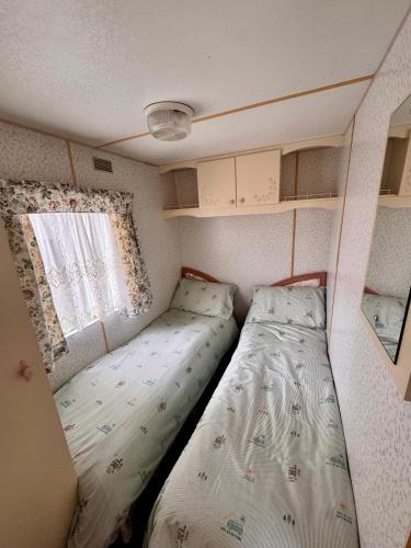 a small bedroom with two beds and a window at No 26 Mountain View in Cockermouth
