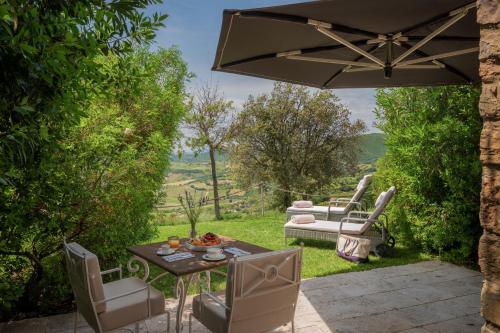 a patio with a table and chairs and an umbrella at Castello di Velona Resort, Thermal SPA & Winery in Montalcino