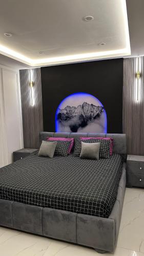 a bedroom with a large bed with a blue background at Luxury Private Top Floor Apartment in Heart of Bahria Town in Lahore