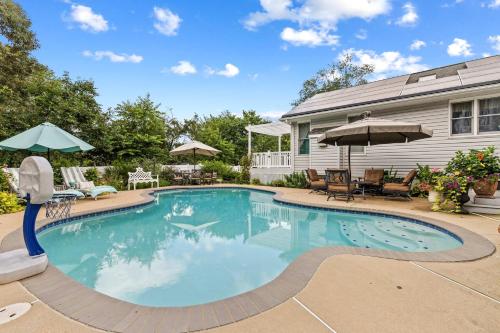 a swimming pool with chairs and umbrellas next to a house at New The Pool Loft at Poplar Hill in Annapolis
