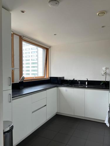 a white kitchen with a sink and a window at Luxury property with stunning views of Canary Warf in London