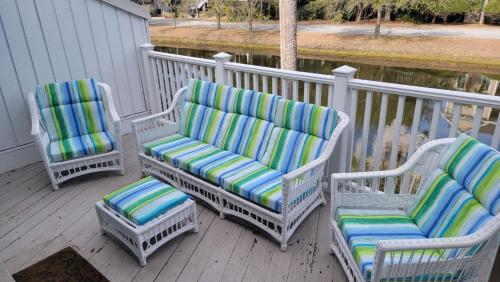 three chairs with striped cushions sitting on a porch at Elegant 3 BR 3 BA Wild Dunes Gated Resort Villa with 2 Golf Courses, Beach and Pool in Isle of Palms