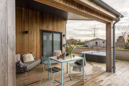 a patio with a table and a couch and a tub at Charterhouse, Strawberryfield Park in Cheddar