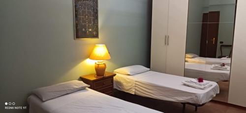 a room with two beds and a lamp on a table at Serendipity in Grottaferrata