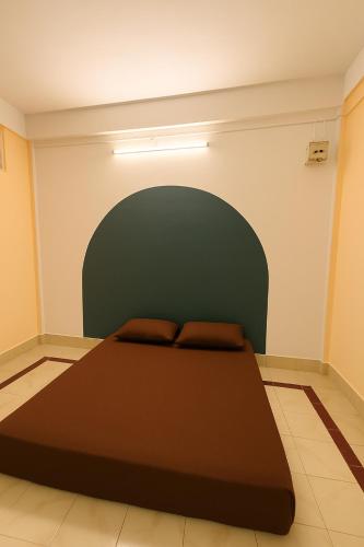 a bedroom with a large bed with a green headboard at Ghar Homestay in Silchar