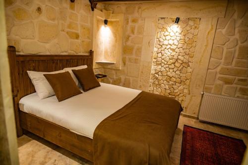 a bedroom with a bed and a stone wall at Senior Stone House in Nevsehir