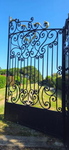 a black gate with a view of a garden at Domaine du lagon bleu in Comps
