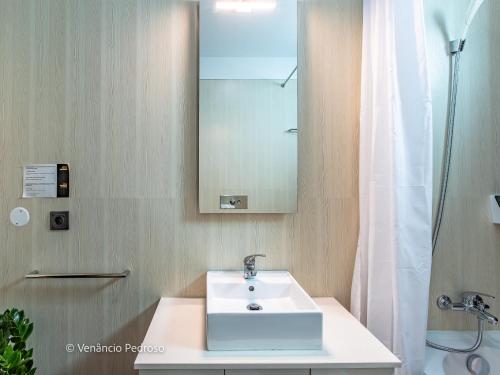 a bathroom with a sink and a mirror and a shower at Ericeira Coxos Beach Lodge in Santo Isidoro