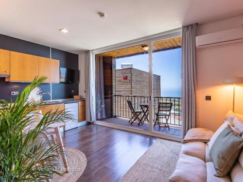 a living room with a couch and a kitchen with a balcony at Ericeira Coxos Beach Lodge in Santo Isidoro